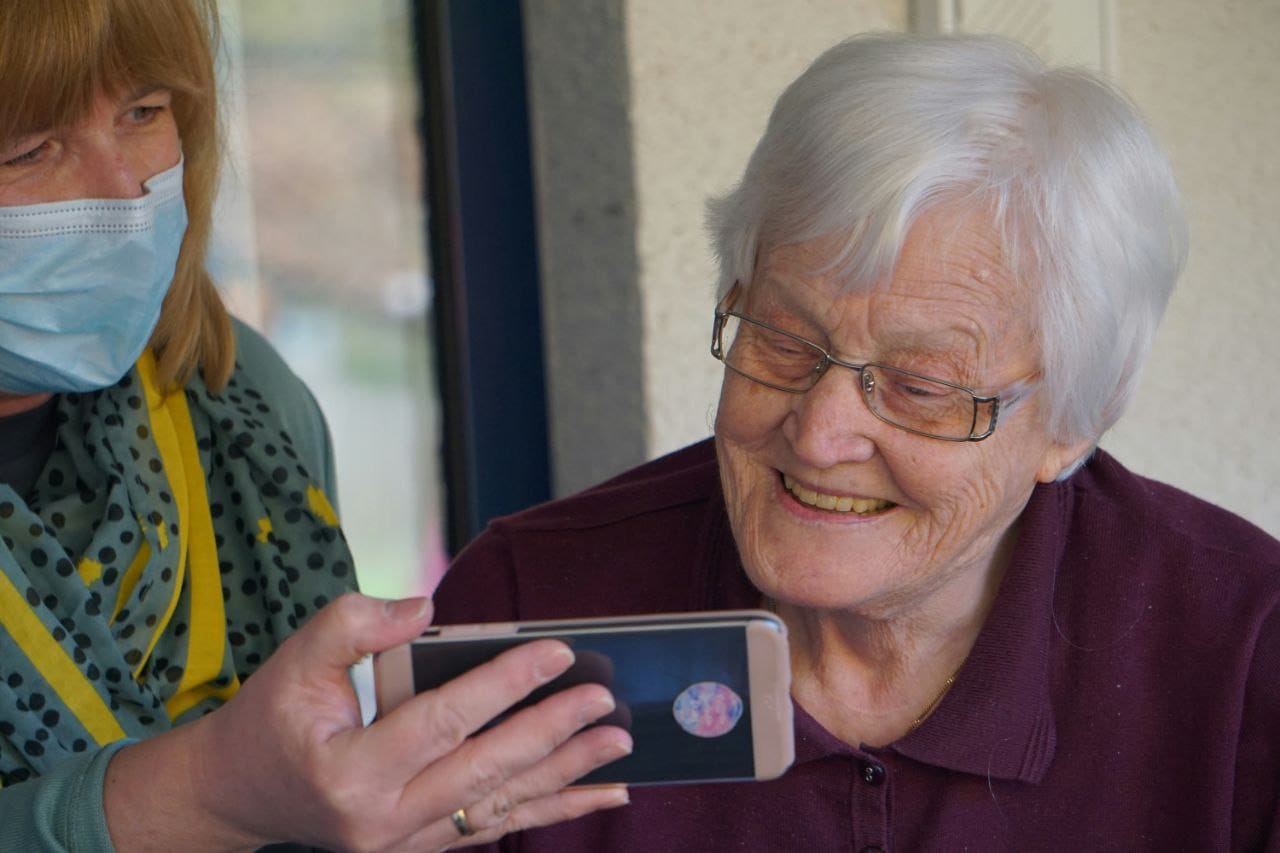 Senior being assisted with smartphone